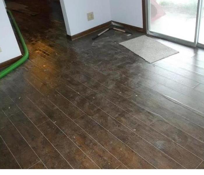 wood floor that has damage with some boards pulled up 