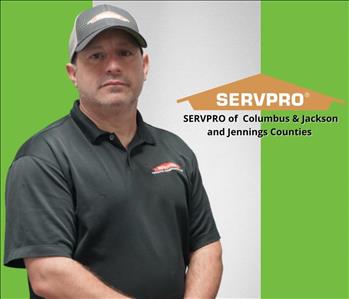 Man looking at camera with green and white background and a servpro logo to the right of him 