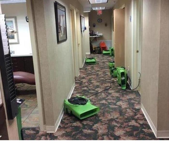 a hallway at a business that had water damage with green SERVPRO airmovers throughout helping to dry things out 